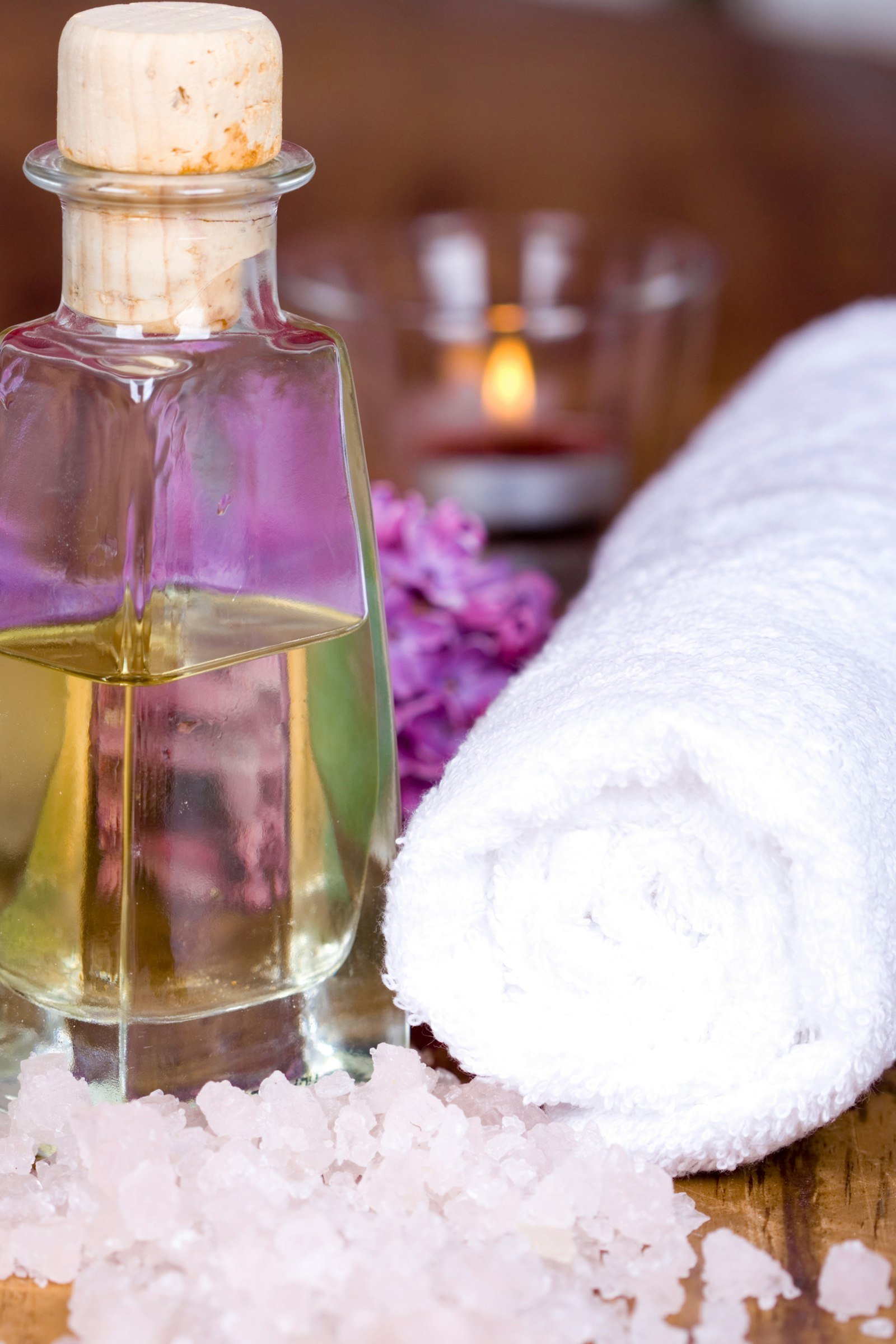 Massageöl, Kerzenlicht und weiche Handtücher als Sinnbild für die Behandlung