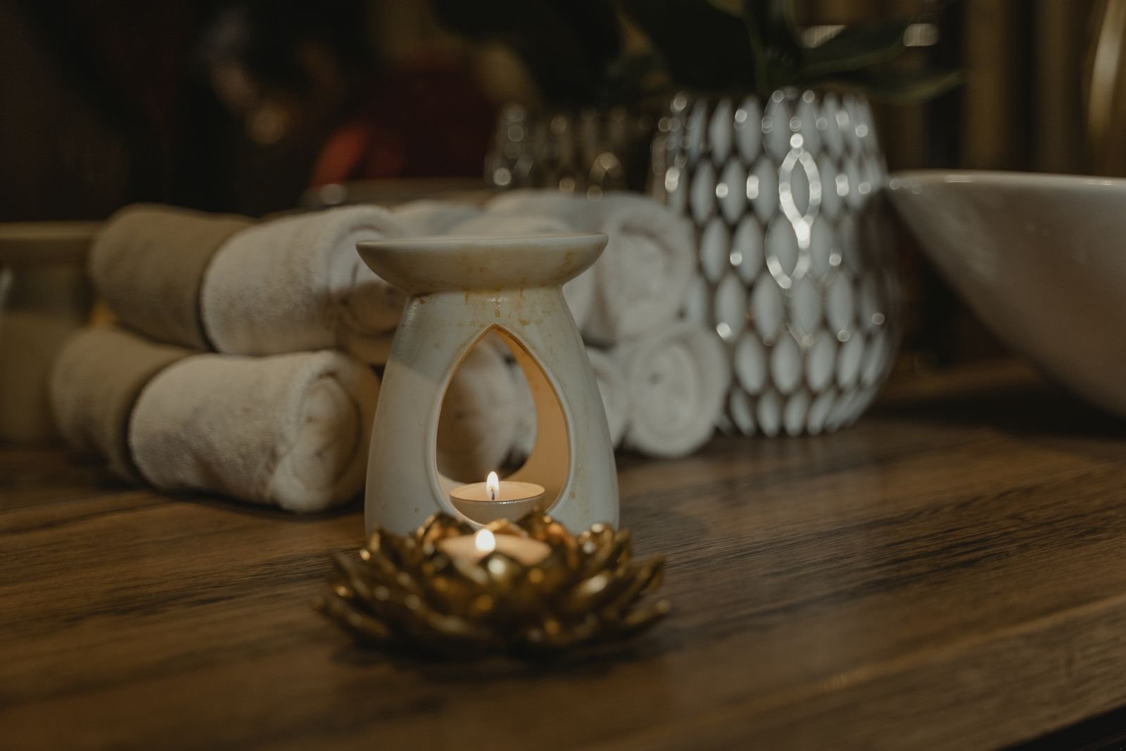 Duftlampe mit Teelicht und Handtücher als Sinnbild für die energetische Massage